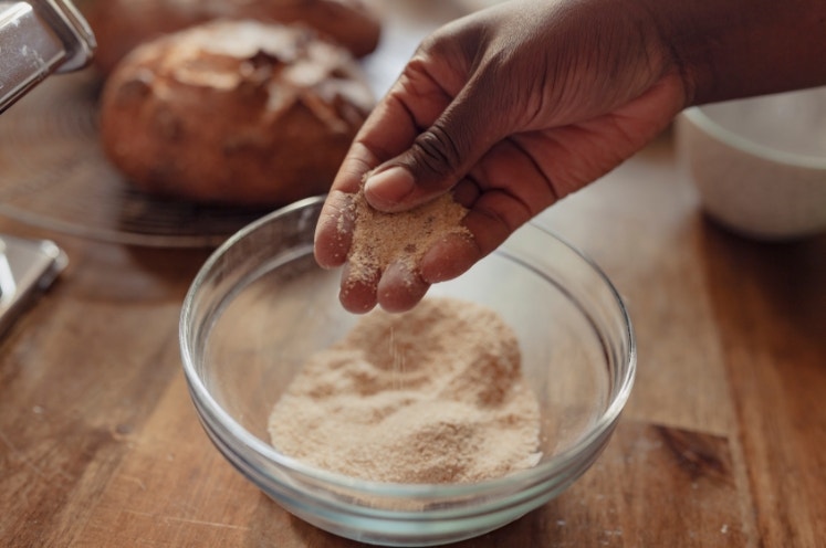 A baker tests the flour she just milled with her hands and fingers