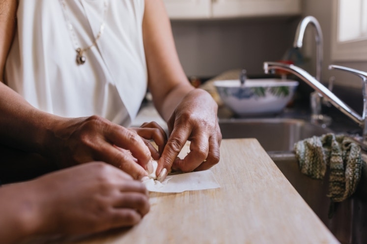 Grandmother making spring rolls with grandchild