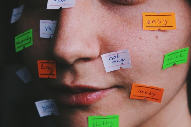 close up portait of young womans face with price tag labels with words as gender roles, social norms, stereotypes, taboos society puts on women