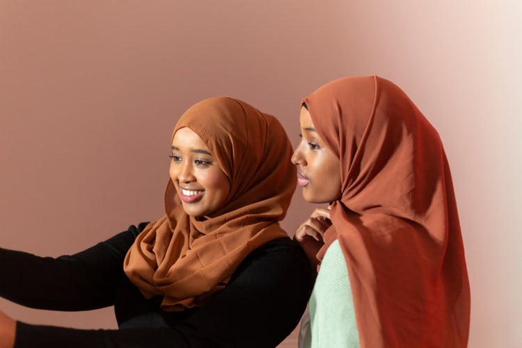 two muslim women smiling on brown palette; Black Muslim Women taking a selfie