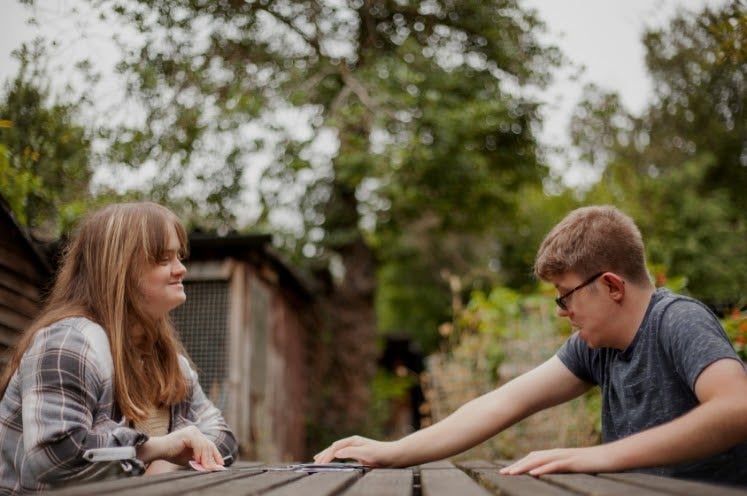Young couple with Down Syndrome and Foetal Alcohol Syndrome playing cards outdoors