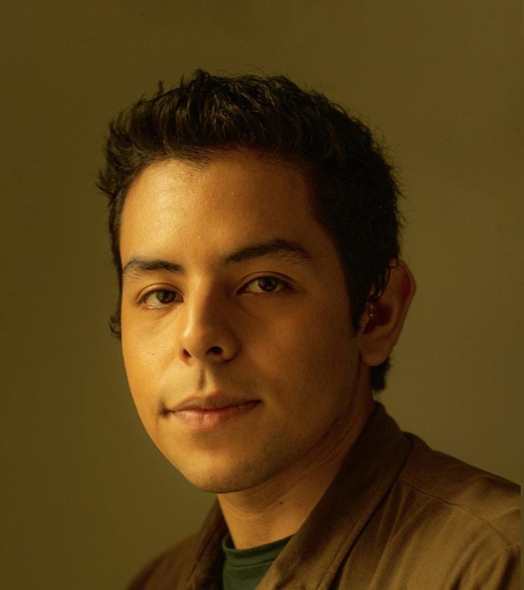Artistic portrait of a young Peruvian Latino, with short black hair. He is sporting a green shirt and polo on a yellow background.
