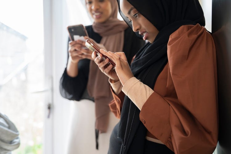 Young Black Muslim girl checking phone