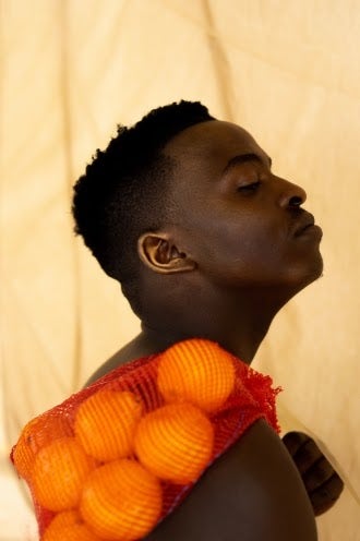 Young black man holding sack of oranges