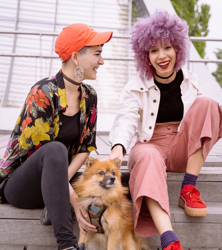 Gender nonbinary couple smiling and happy, lesbian in orange hat, lesbian with purple hair, friends and lovers, chosen family