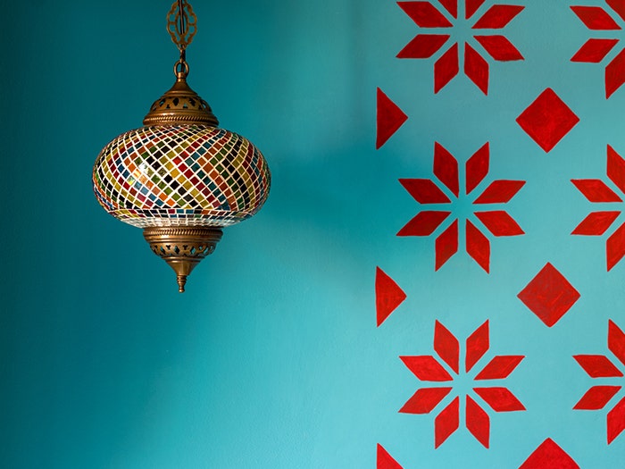 Beautiful chandelier light with colorful glass decoration in Indian style. Blue and red patterned backdrop.