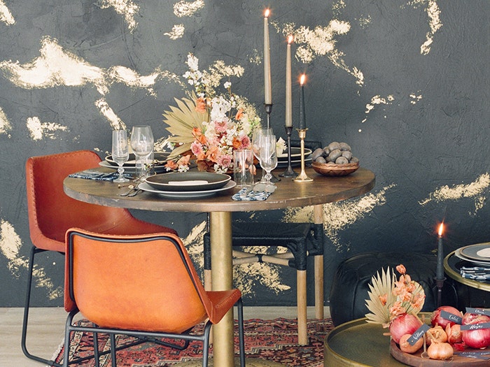 Fall themed home interior decor: table with luxe settings, candles, flowers, and orange chairs.