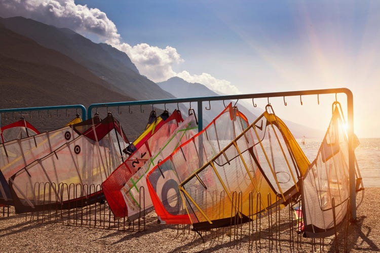 Kite surfing sails on rack outside. Sunset, beach, mountains.