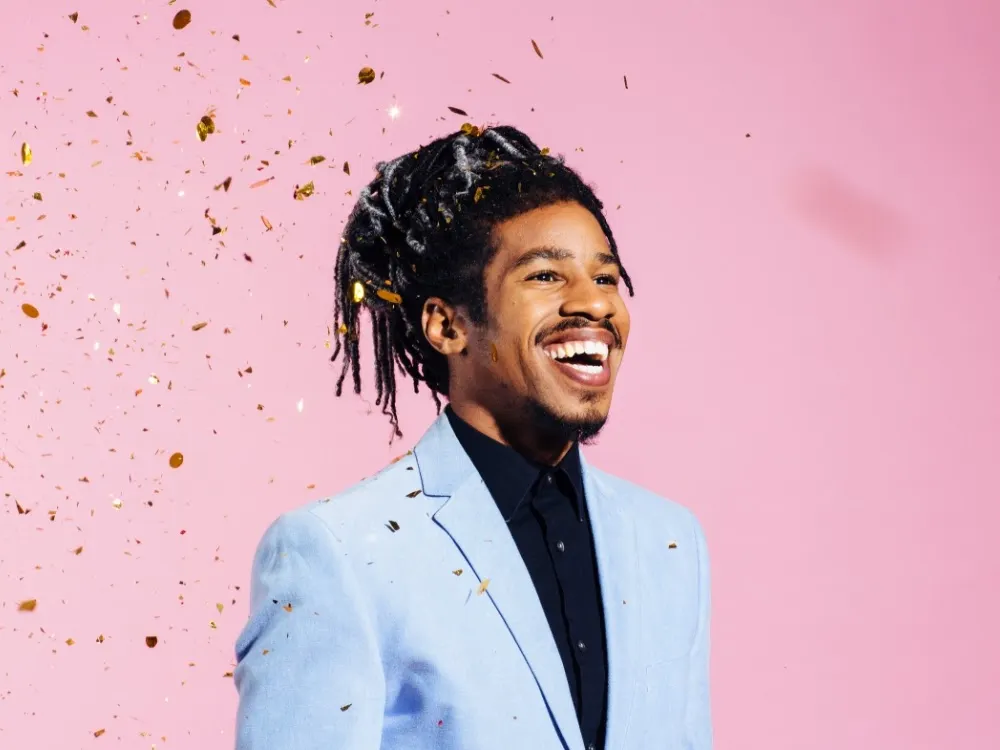 Portrait of a man with cool hair laughing, against studio background By Carlos David