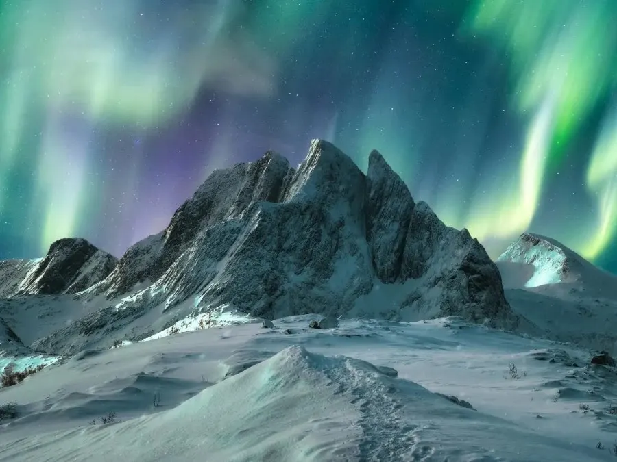 Aurora borealis over majestic mountain in snowy on Segla Island By mumemories